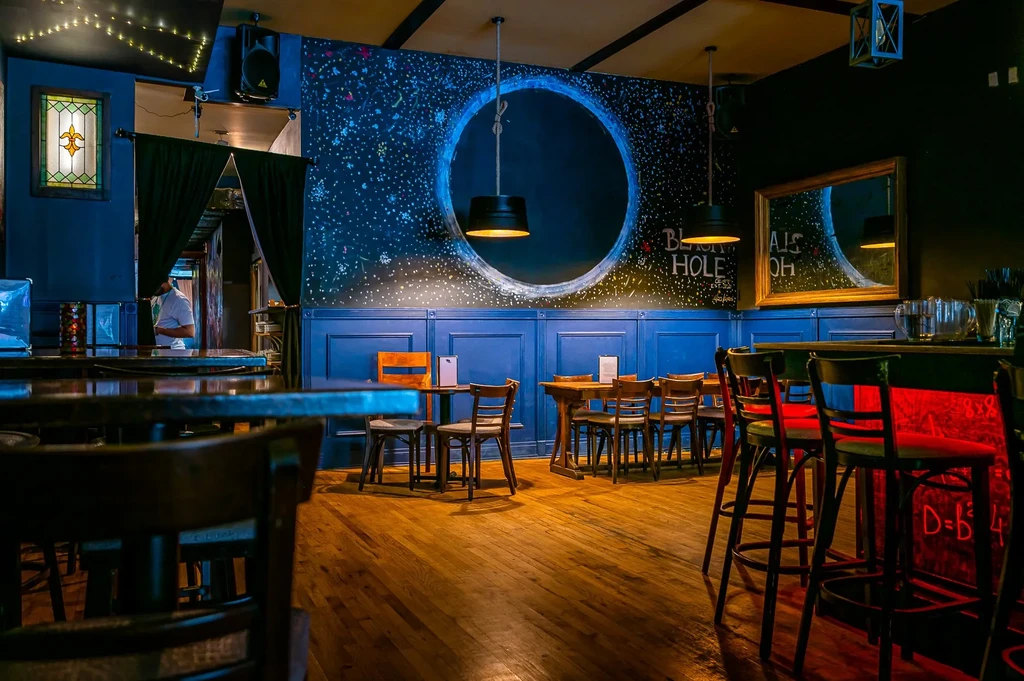 Dimly lit bar with dark blue wainscoting and a starry night wall.