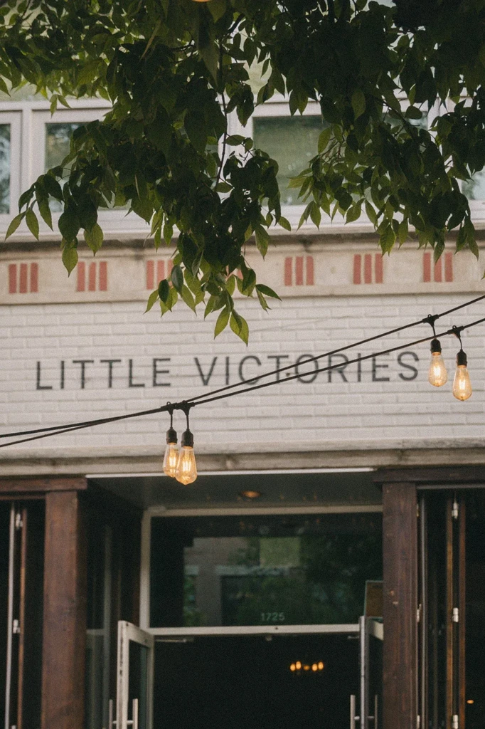 Exterior of Little Victories building with Edison lights and glass doors.
