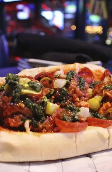 Close-up of a meatball sub with diverse toppings.