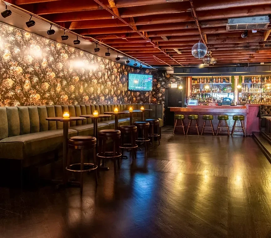 Dimly lit bar or restaurant interior with booth seating and a bar.