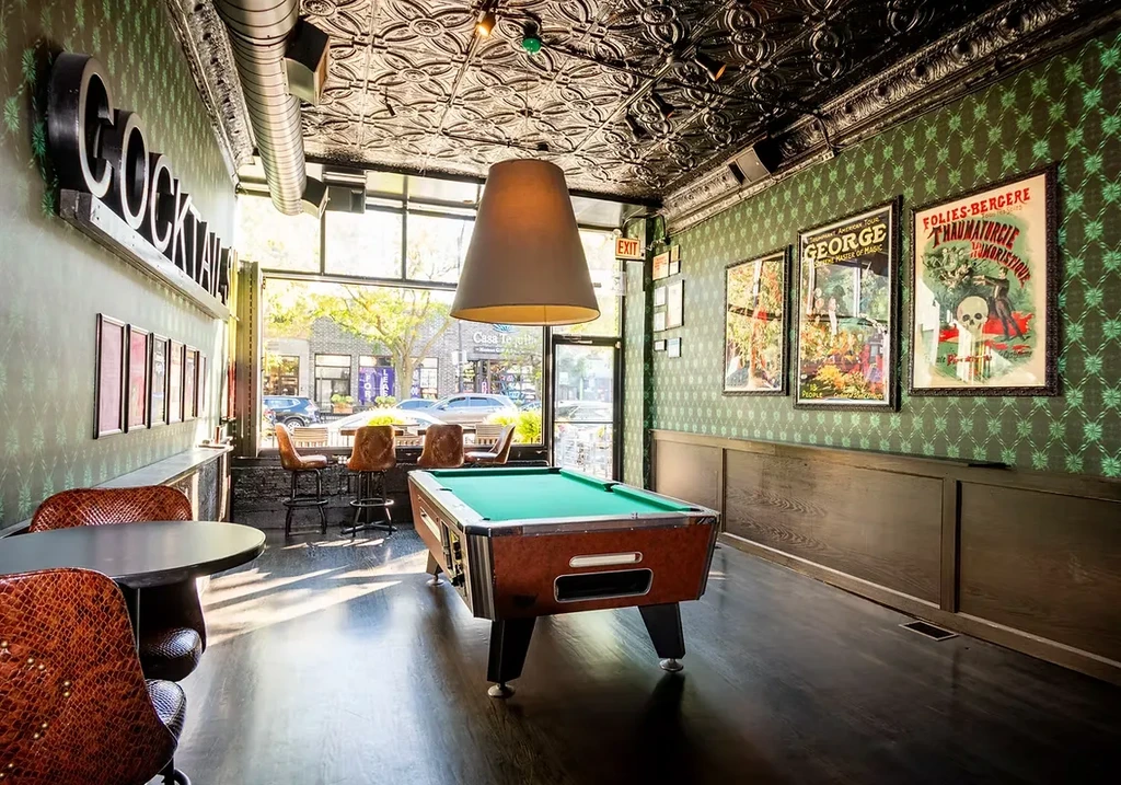Green-felt pool table in an ornate bar with a "COCKTAILS" sign.