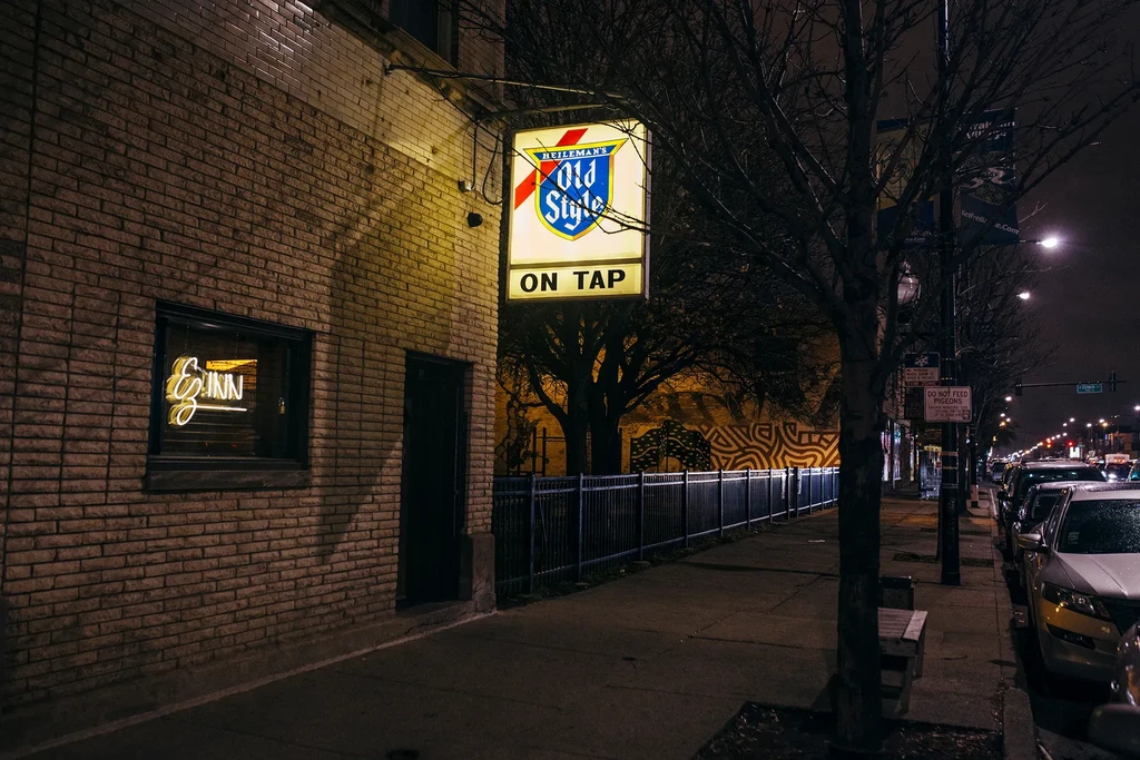 Nighttime street scene featuring the exterior of the "Ez Inn" bar.