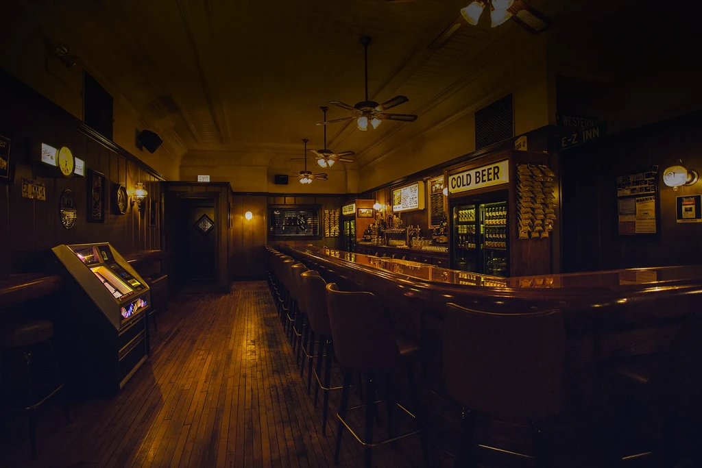 Interior of a dimly lit, traditional bar with a wooden counter and jukebox.