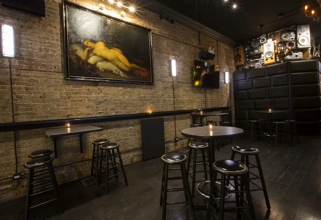 Rustic bar with brick walls, nude painting, and speaker display.