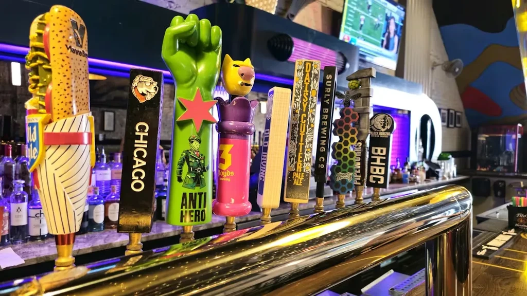 Close-up of beer tap handles at a bar with purple lighting.