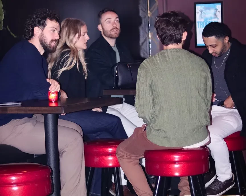 Five people on bar stools in a dimly lit bar.