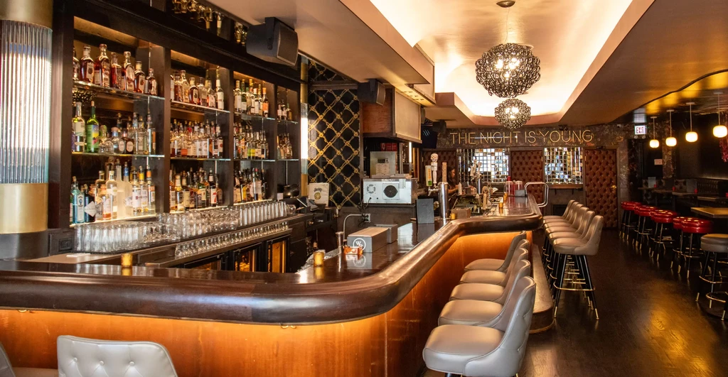 Stylish bar interior with a long wooden counter and liquor display.