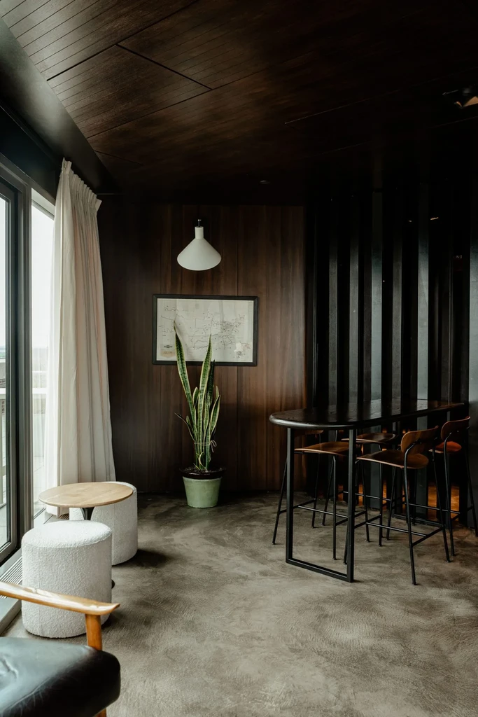 Modern restaurant interior with dark wood paneling, varied seating, and warm lighting.