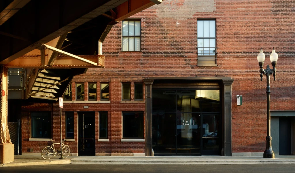 Brick building with a glass storefront under an elevated train track.