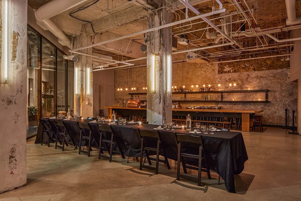 Industrial-chic restaurant with a dining table and bar area.