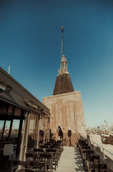Rooftop restaurant with a cityscape view and architectural spire.
