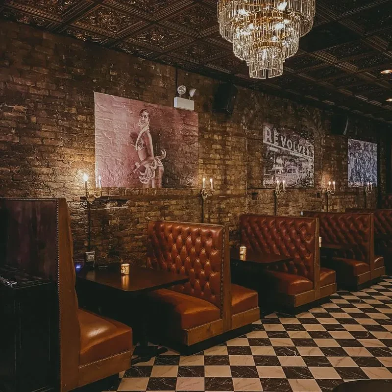 Vintage bar interior with brick walls, leather booths, and chandelier.