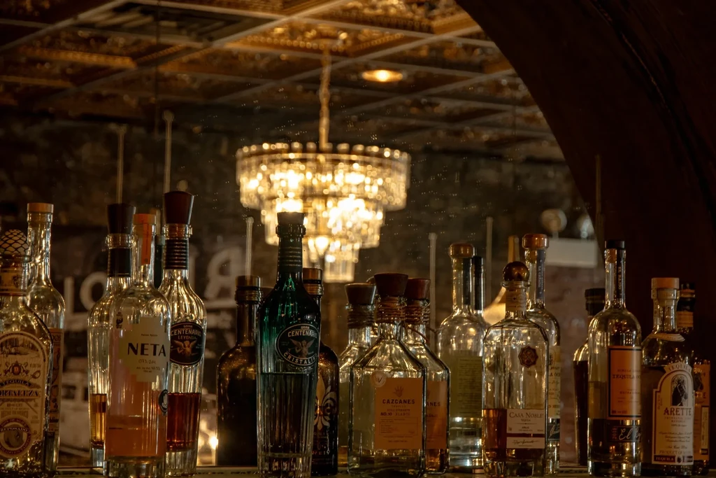 Liquor bottles, primarily tequila, displayed on a bar shelf.