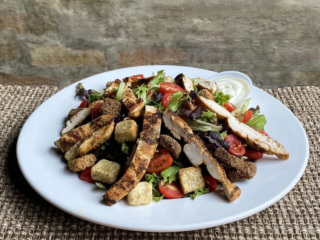 Grilled chicken salad with lettuce, tomatoes, croutons, and dressing.