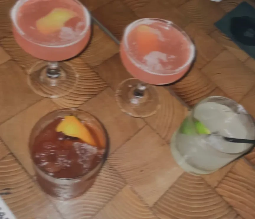 Four alcoholic drinks on a woven wooden table.