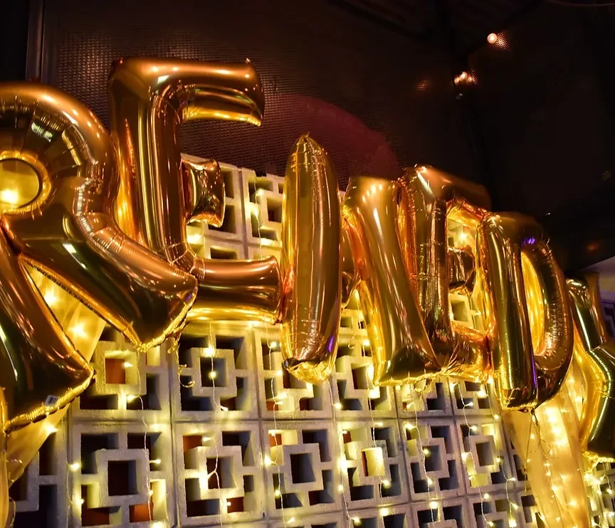 Gold foil balloons spelling "RELOAD" against a lit concrete wall.