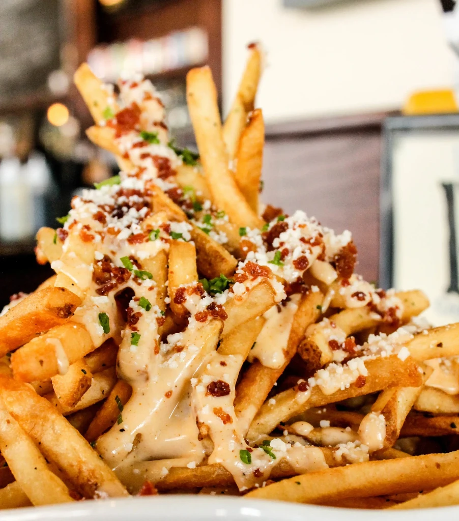 Crispy french fries loaded with cheese, bacon, sauce, and herbs.