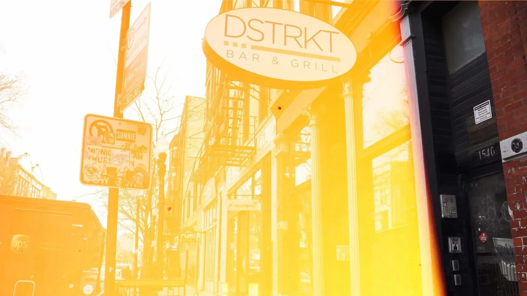 Exterior view of DSTRKT BAR & GRILL with strong yellow-orange color cast.