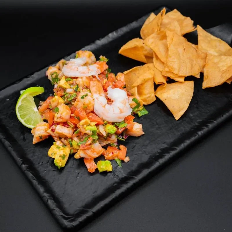Shrimp ceviche with diced vegetables, lime, and tortilla chips.