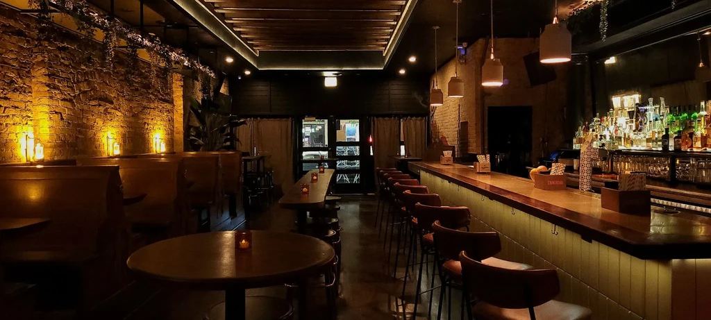 Dimly lit bar interior with booths, tables, and a stocked bar.