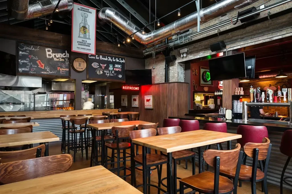 Industrial-rustic restaurant interior with wooden tables, stools, and chalkboards.