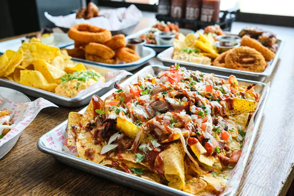 Nachos, onion rings, and other appetizers on metal trays.
