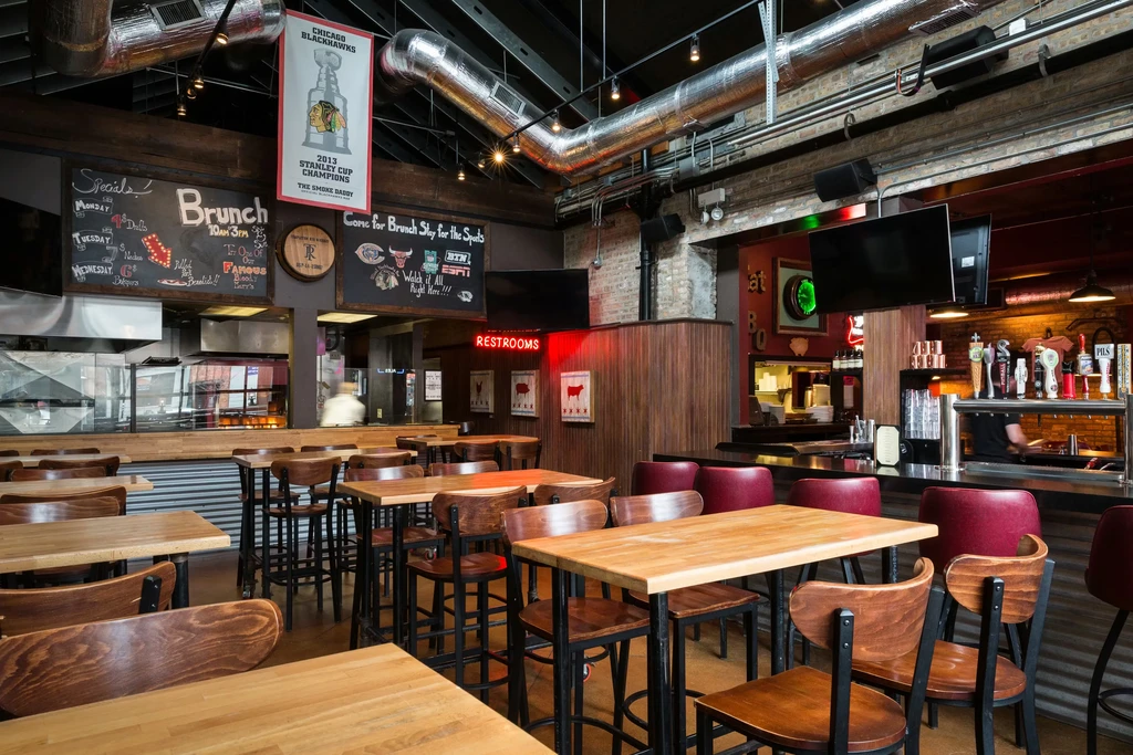 Interior of a casual restaurant with tables, chairs, and a bar.