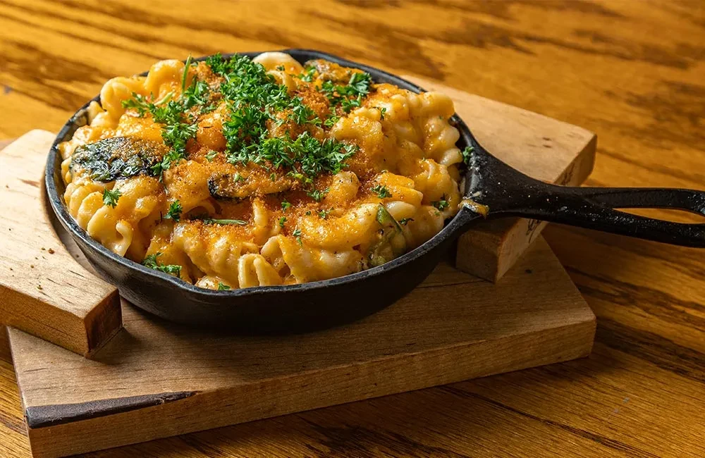Mac and cheese in a skillet, topped with breadcrumbs and parsley.