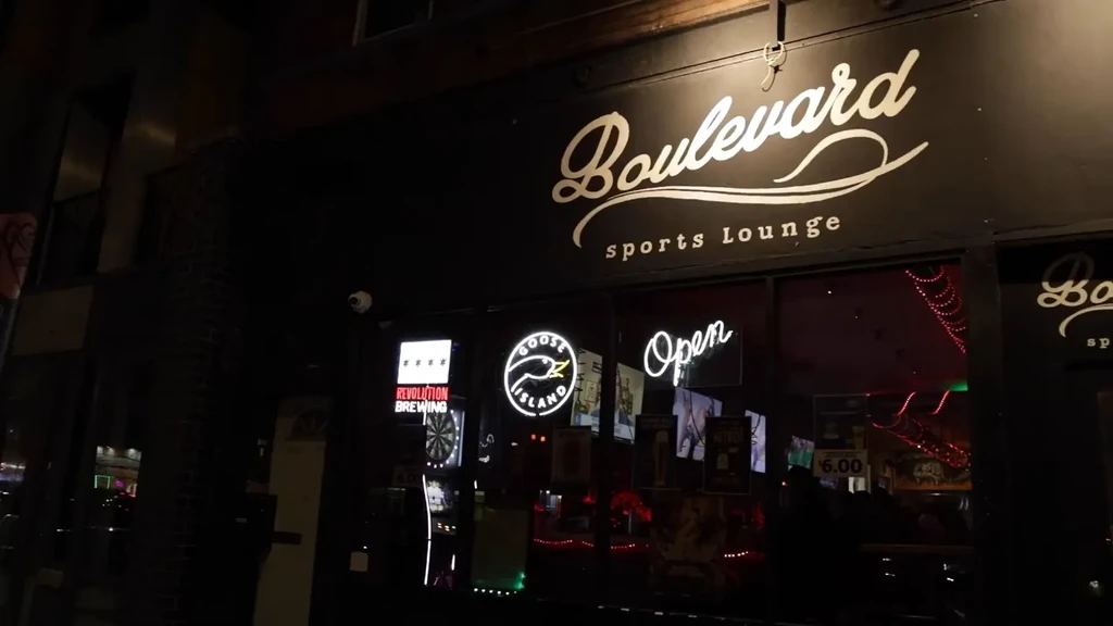 Exterior of Boulevard Sports Lounge at night, visible neon signs.