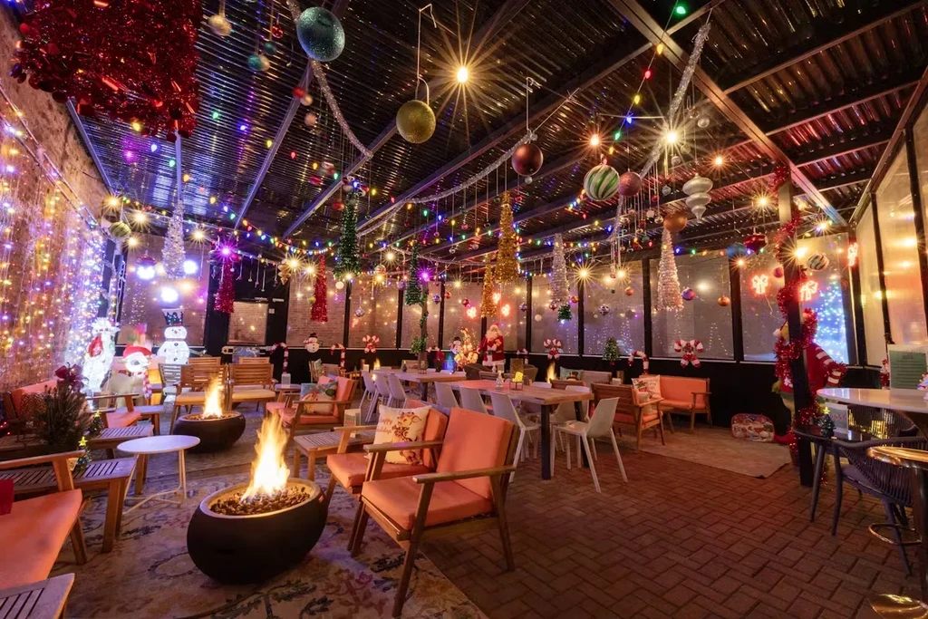 Restaurant interior decorated for Christmas with lights, baubles, and fire pits.