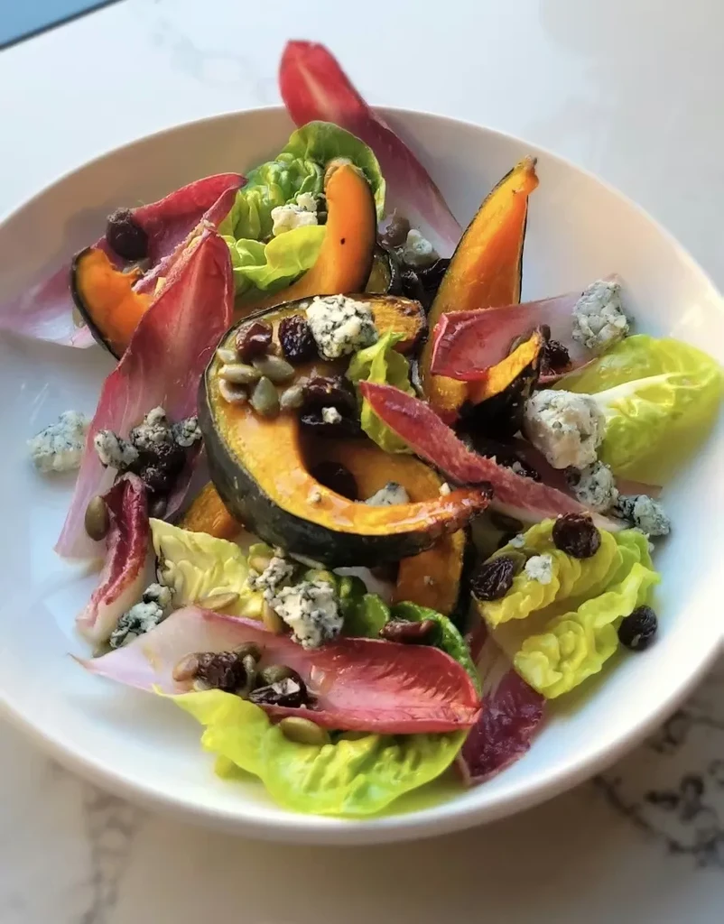 Overhead shot of salad with squash, lettuce, blue cheese, and seeds.