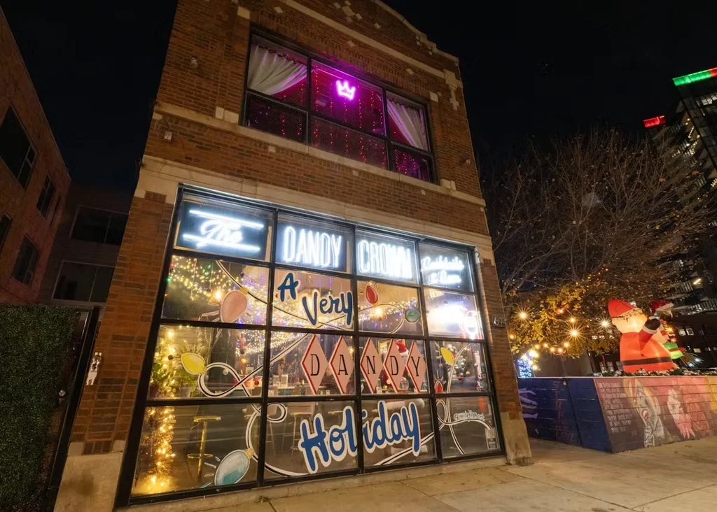 Exterior of The Dandy Crown bar with holiday decorations at night.
