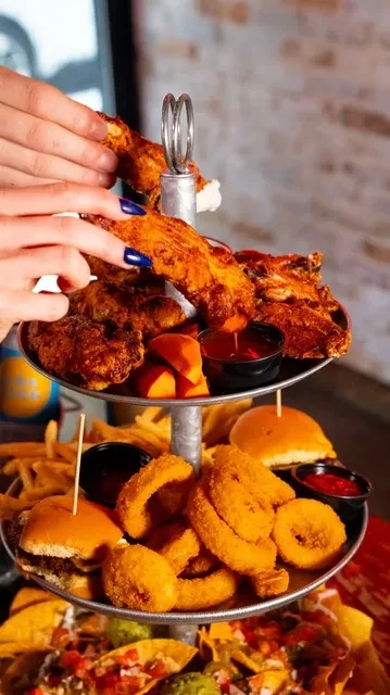 Three-tiered stand overflowing with fried chicken, onion rings, and nachos.