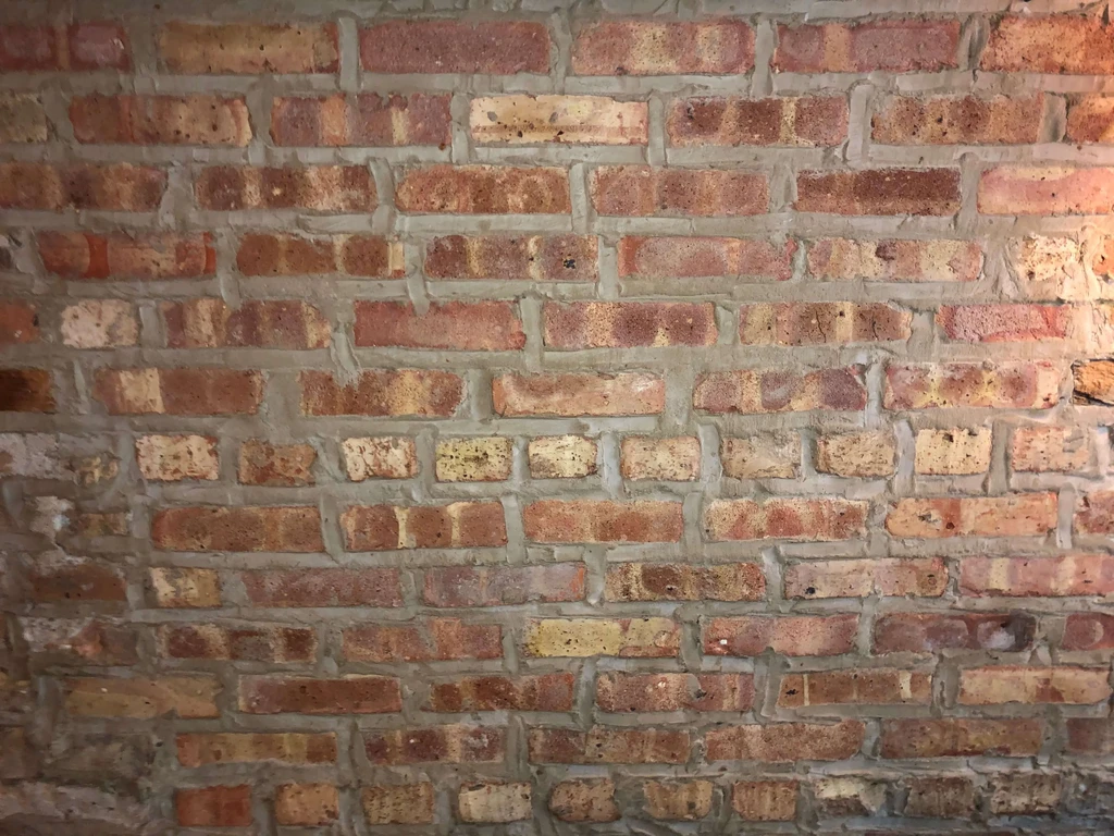 Close-up of a rustic reddish-brown brick wall with grey mortar.