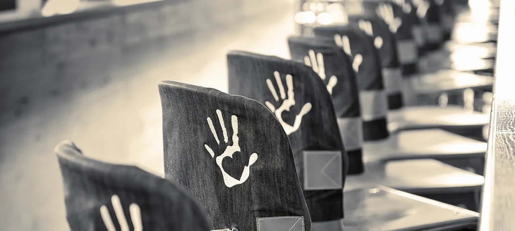 Row of dark denim chairs with white handprint designs.
