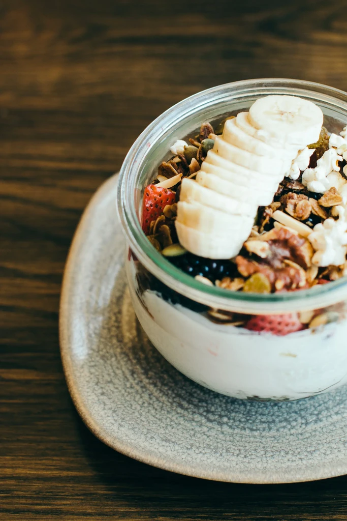 Layered breakfast in a glass jar with fruit, granola, nuts.