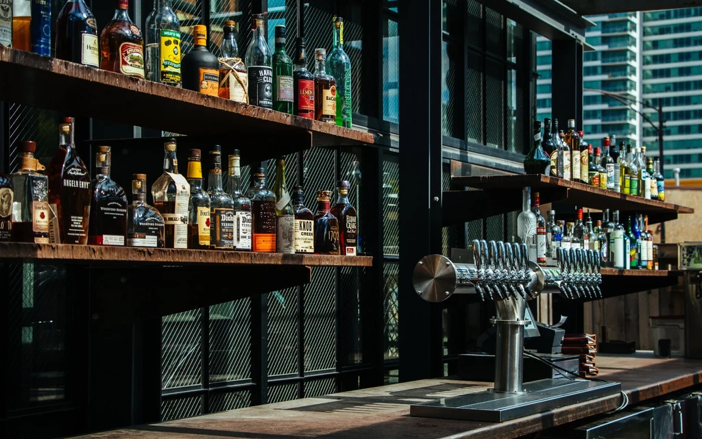 Well-stocked bar with liquor bottles, beer taps, and city background.