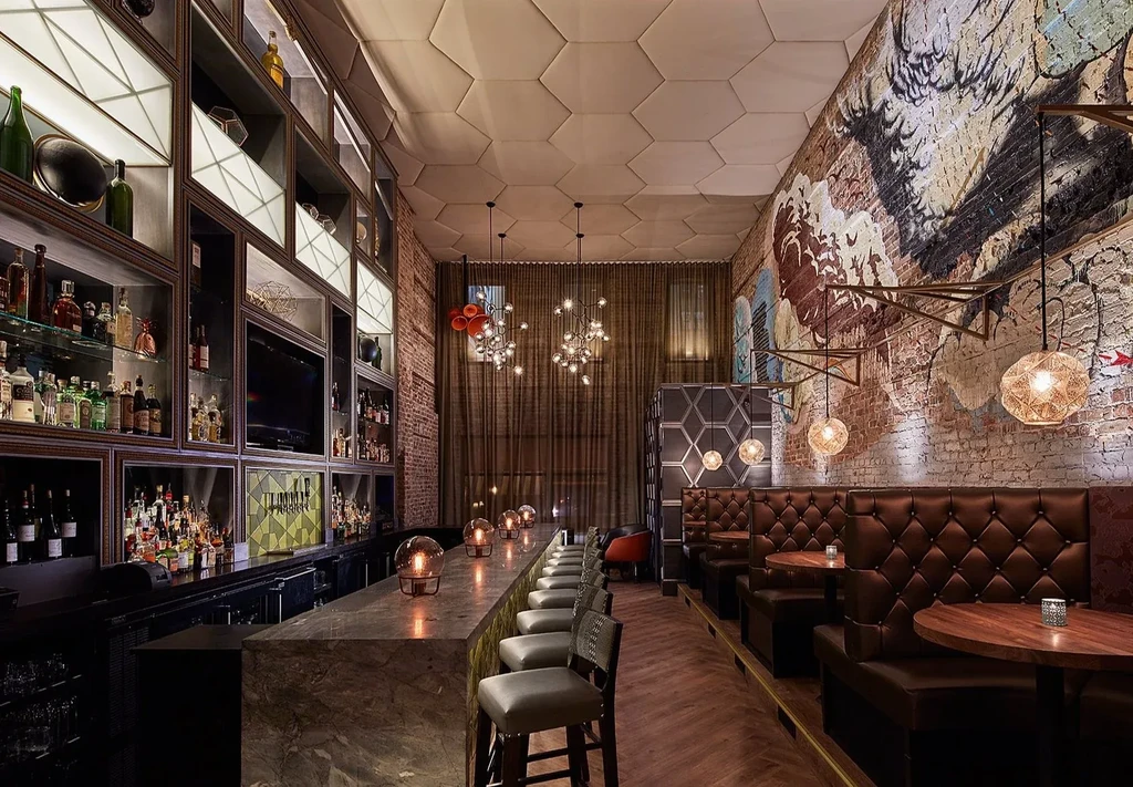 Modern bar and restaurant interior with dark bar and leather booths.