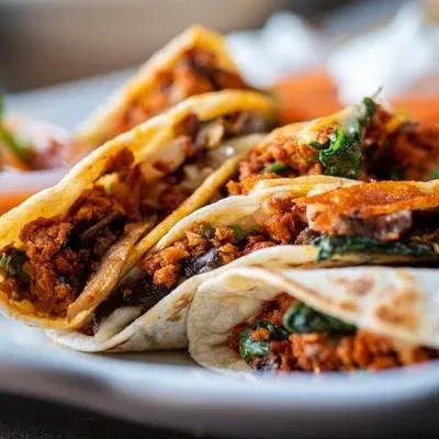 Close-up of several folded tortillas filled with meat and vegetables.
