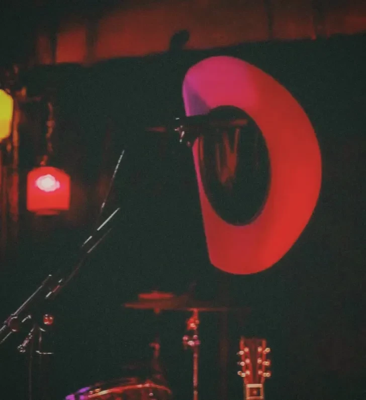 Red cowboy hat on a stand in a dimly lit bar.