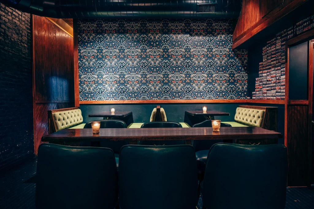 Dimly lit restaurant interior with communal tables and green upholstered booths.