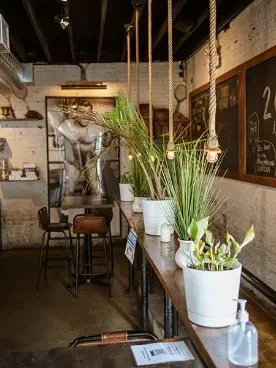 Industrial-chic restaurant interior with a long wooden bar and pendant lights.