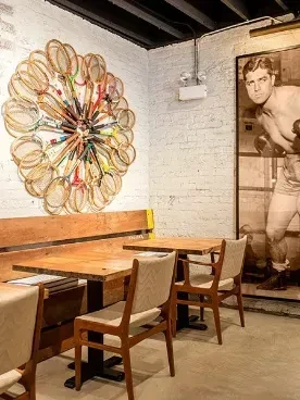 Restaurant interior with exposed brick, wooden benches, and eclectic decor.