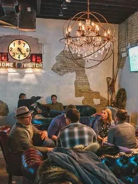 Cozy bar interior with groups of people and unique decor.