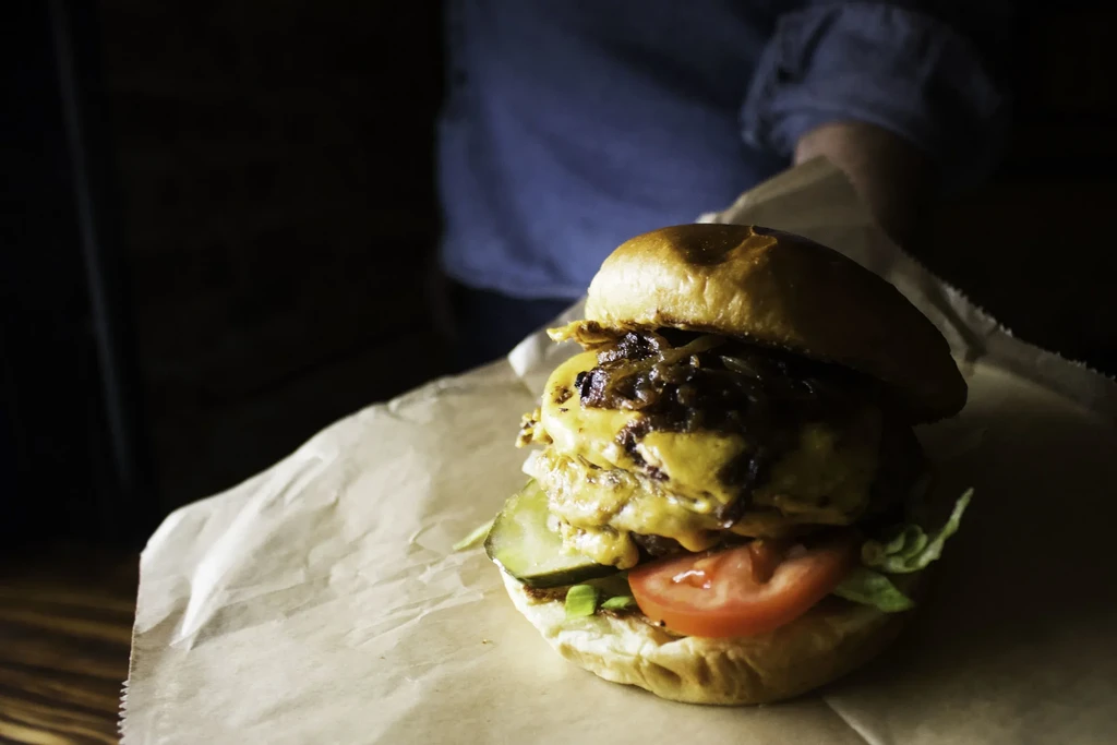 Double cheeseburger with lettuce, tomato, onions, pickle, and melted cheese.