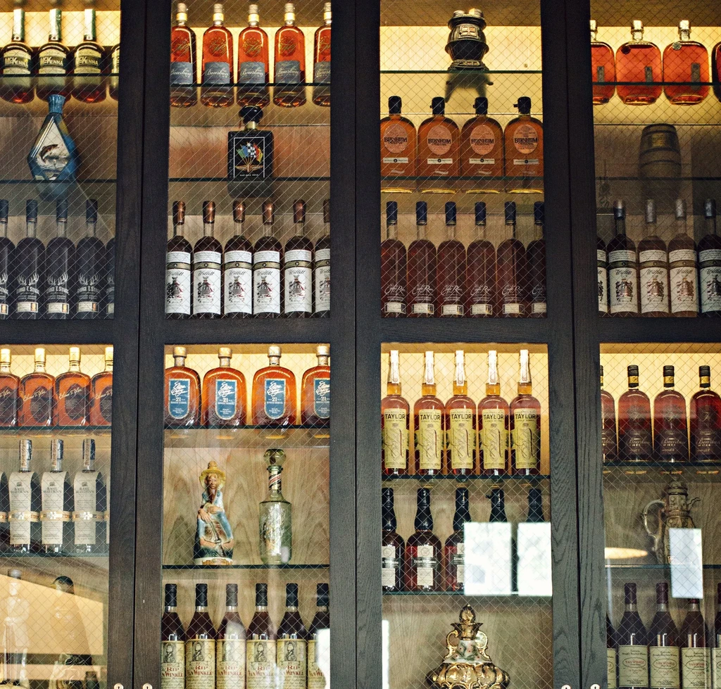 Liquor cabinet with various bottles of whiskey and decorative items.