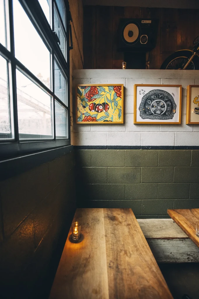 Restaurant interior with dark green walls, window, and framed art.