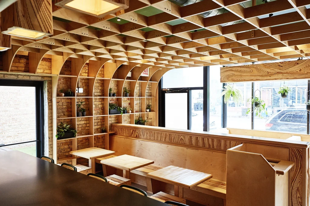 Modern restaurant interior with intricate wood ceiling and shelving.