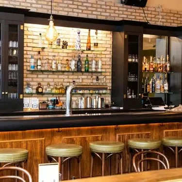 Well-stocked bar with liquor bottles, beer taps, and bar stools.
