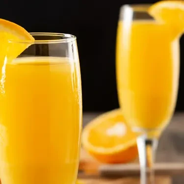 Two orange drinks, one in a tumbler, another in a flute.